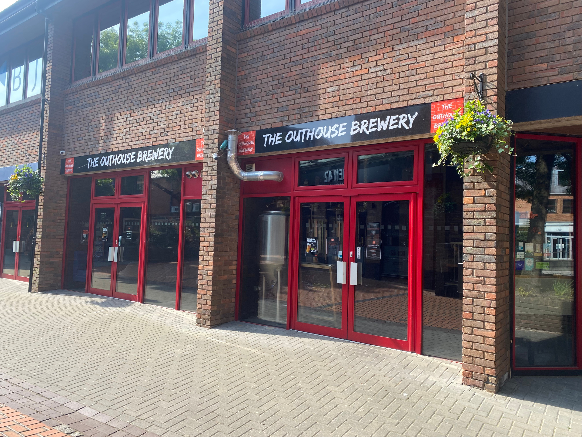 The Outhouse Brewery storefront in Wokingham with red-framed windows and signage